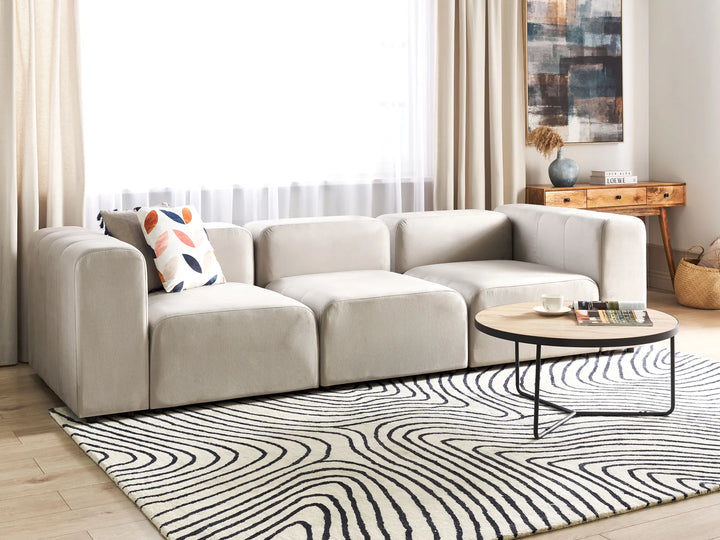Modern living room with a beige sectional sofa, coffee table, and decorative items.