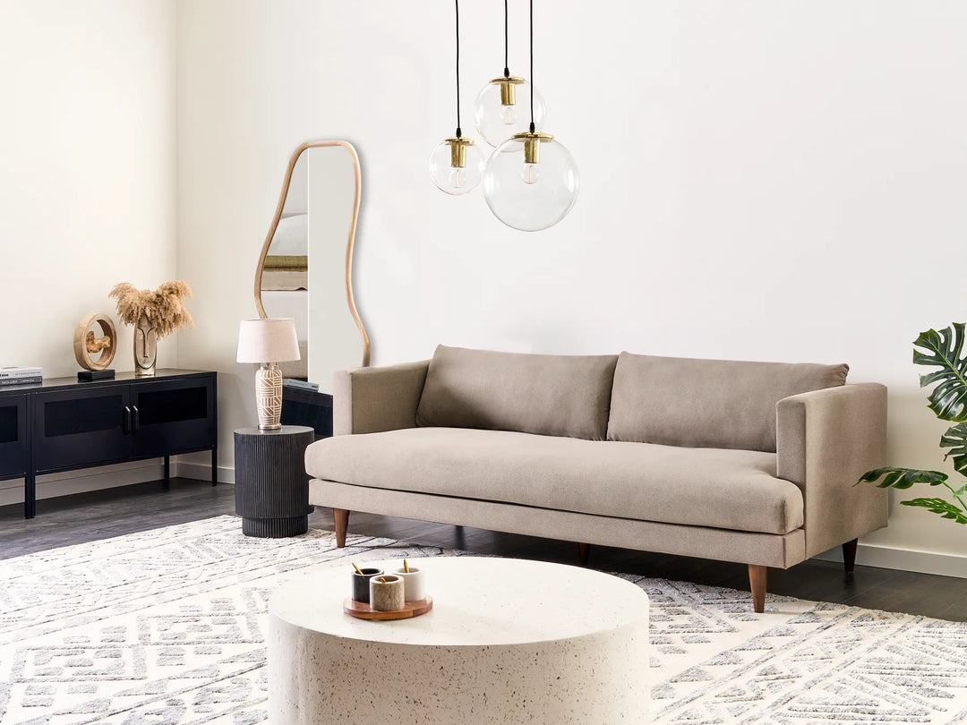 Modern living room with a beige sofa, coffee table, and decorative items.