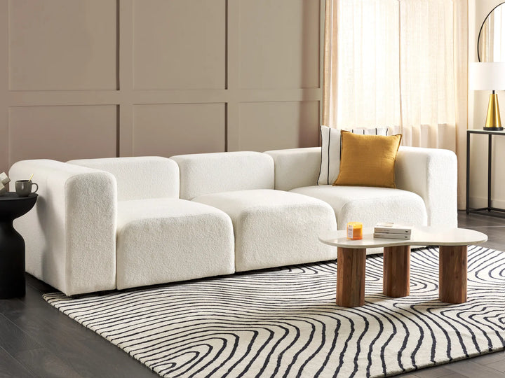 Modern living room with a white sofa, coffee table, and decorative elements.