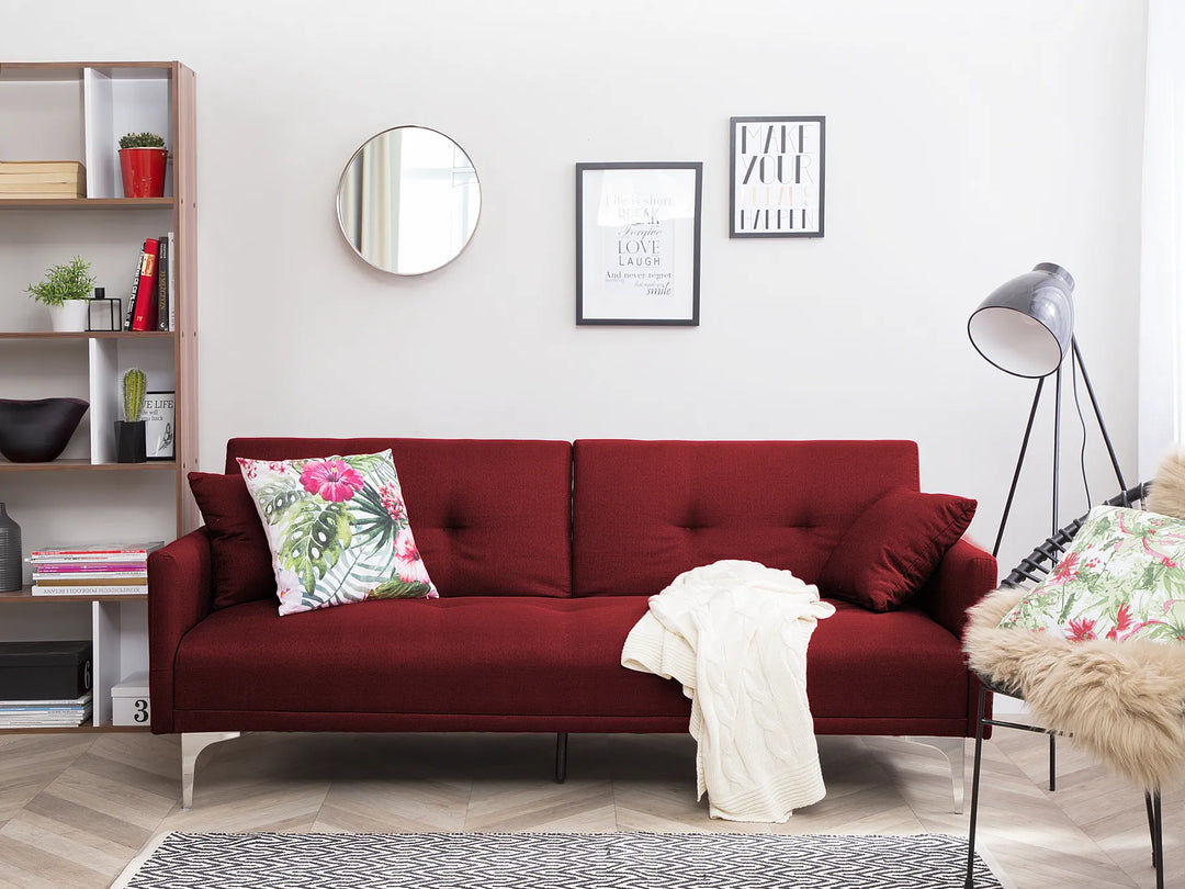 Red sofa in a living room with decorative pillows and a rug.
