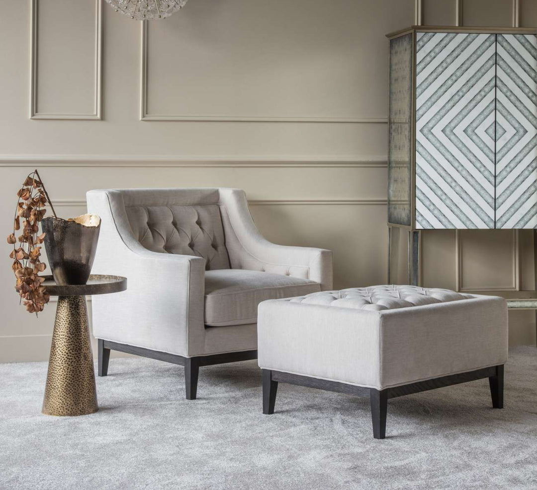Luxury living room with gray armchair, ottoman, and decorative side table.