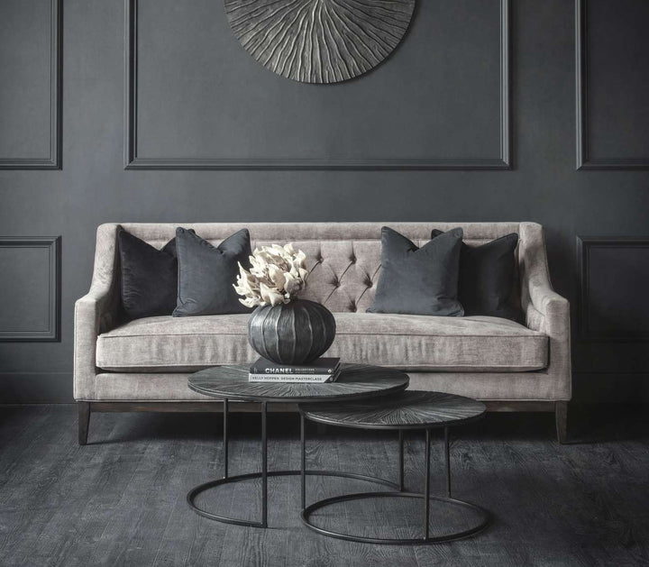 Gray sofa with decorative pillows against a dark gray wall with a circular wall art piece.