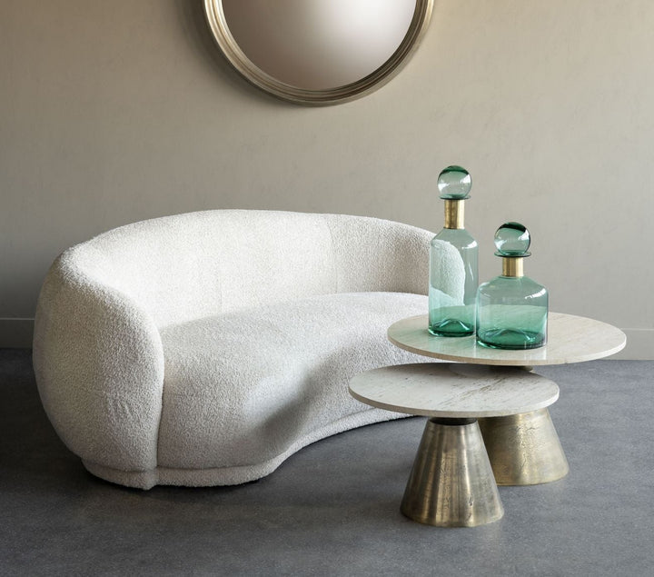 Modern white sofa with decorative tables and mirrors in a minimalistic room.