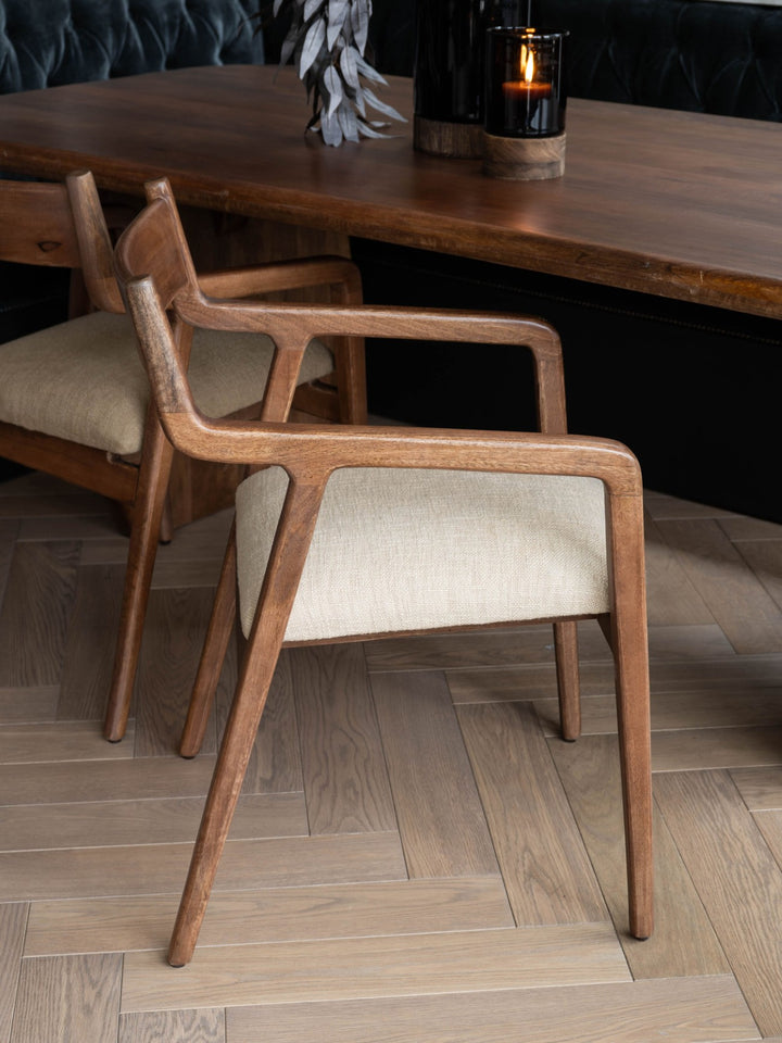 Wooden chair with beige cushion in front of a wooden table.