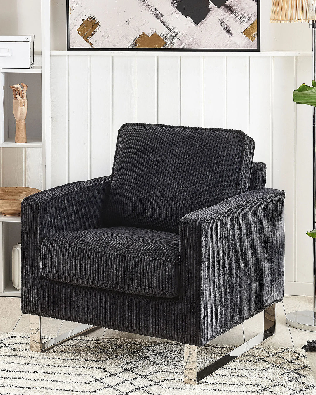 Dark gray armchair in a room with a white wall and decorative elements.