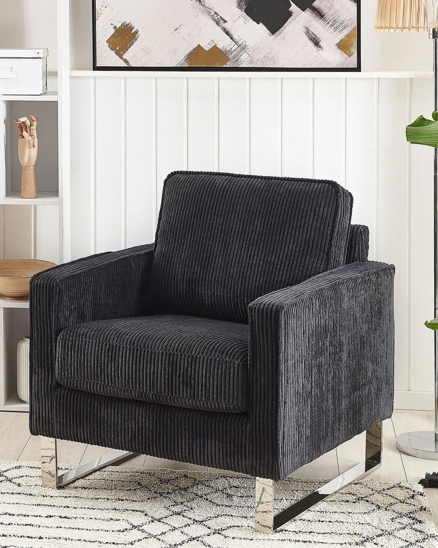 Dark gray armchair in a room with a white wall and decorative elements.