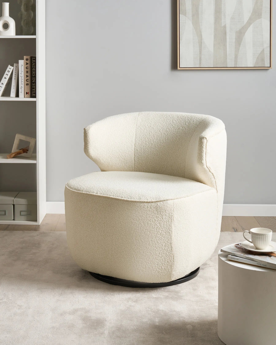 Beige armchair in a modern room with a bookshelf and framed artwork.