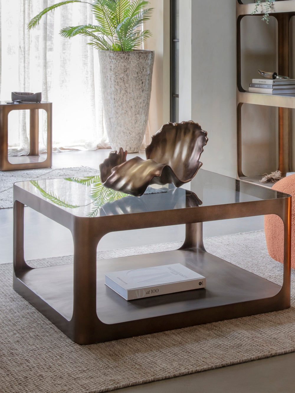 Glass coffee table with a decorative shell and plant in a modern living room setting.