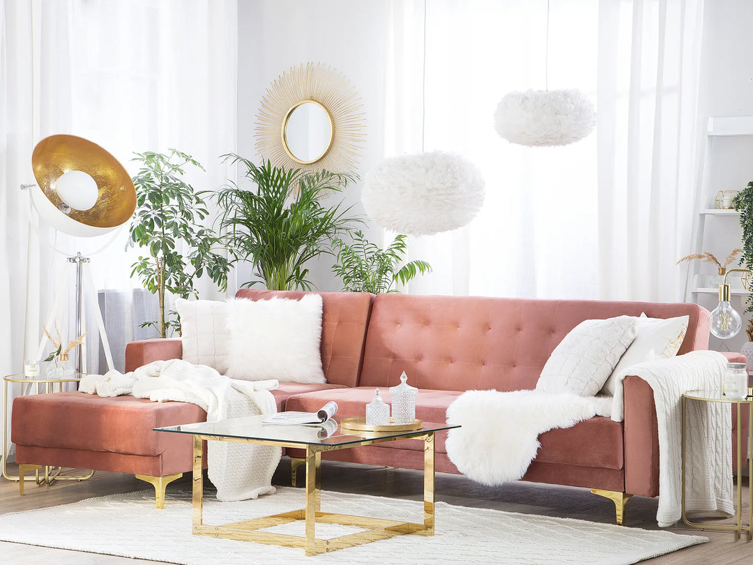 Modern living room with a pink sofa, gold coffee table, and decorative plants.