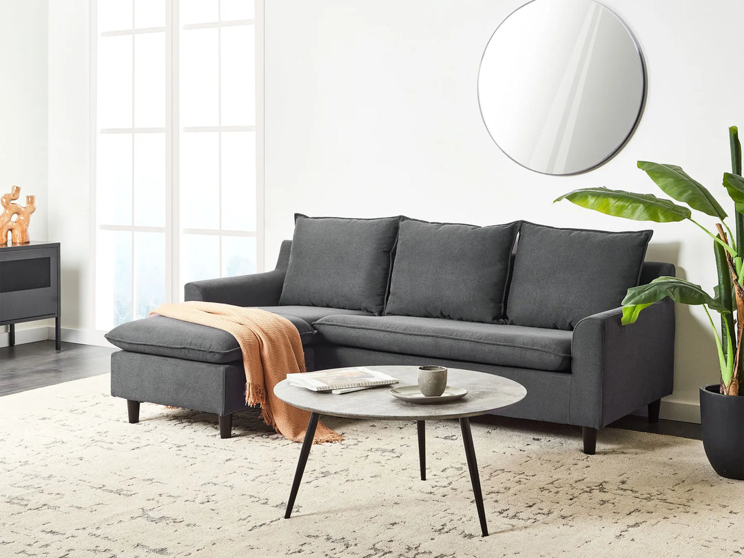 Gray sectional sofa in a living room with a round coffee table and decorative items.