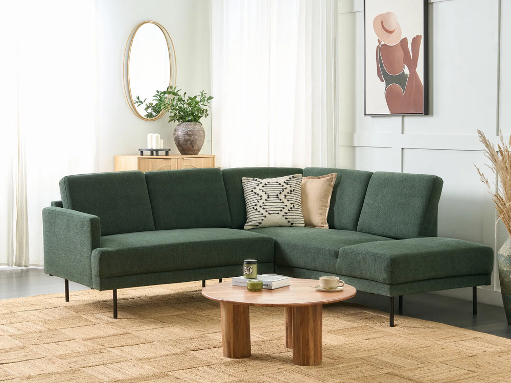 Green sectional sofa in a living room with a wooden coffee table and decorative items.