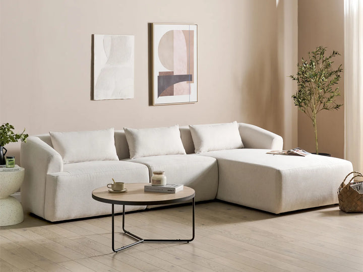 Modern living room with a white sectional sofa, wooden coffee table, and abstract art on the wall.