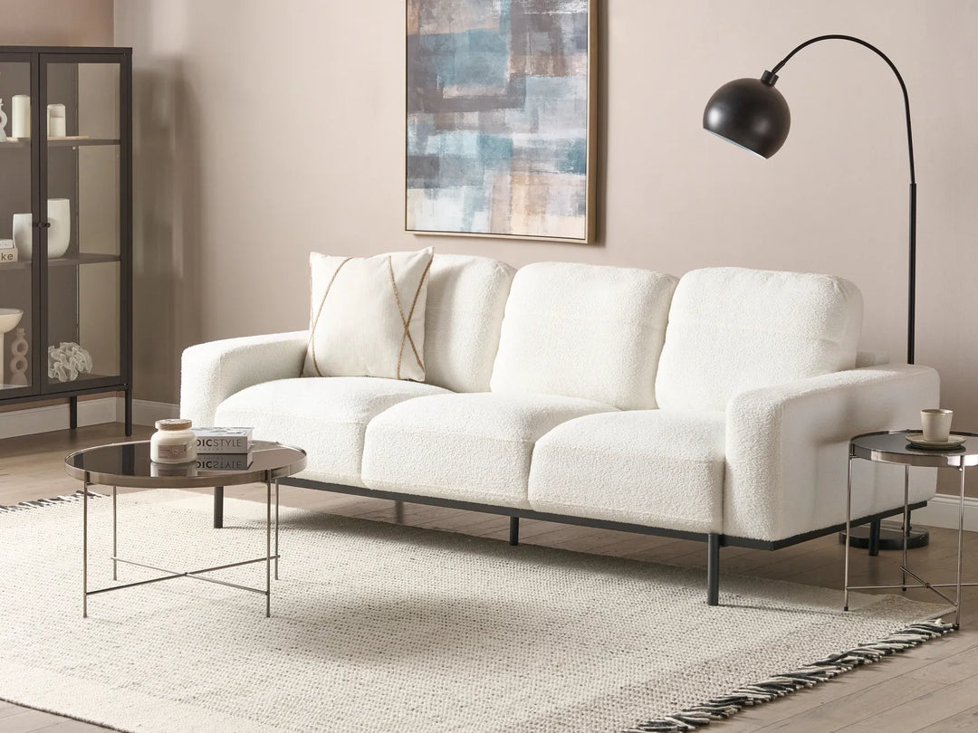 White sofa in a living room with a lamp, coffee table, and decorative items.