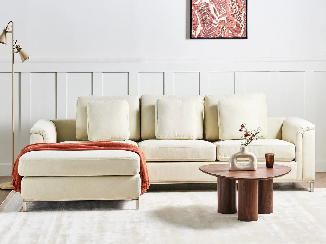 Beige sectional sofa in a living room with a wooden coffee table and decorative elements.