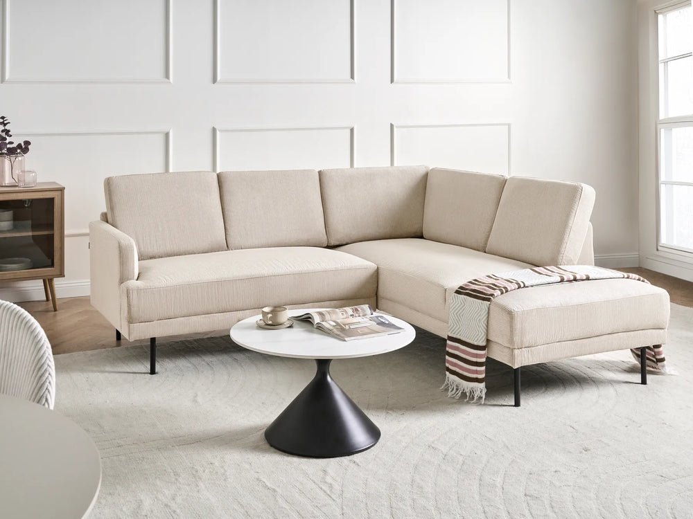 Beige sectional sofa in a modern living room with a white coffee table and decorative items.