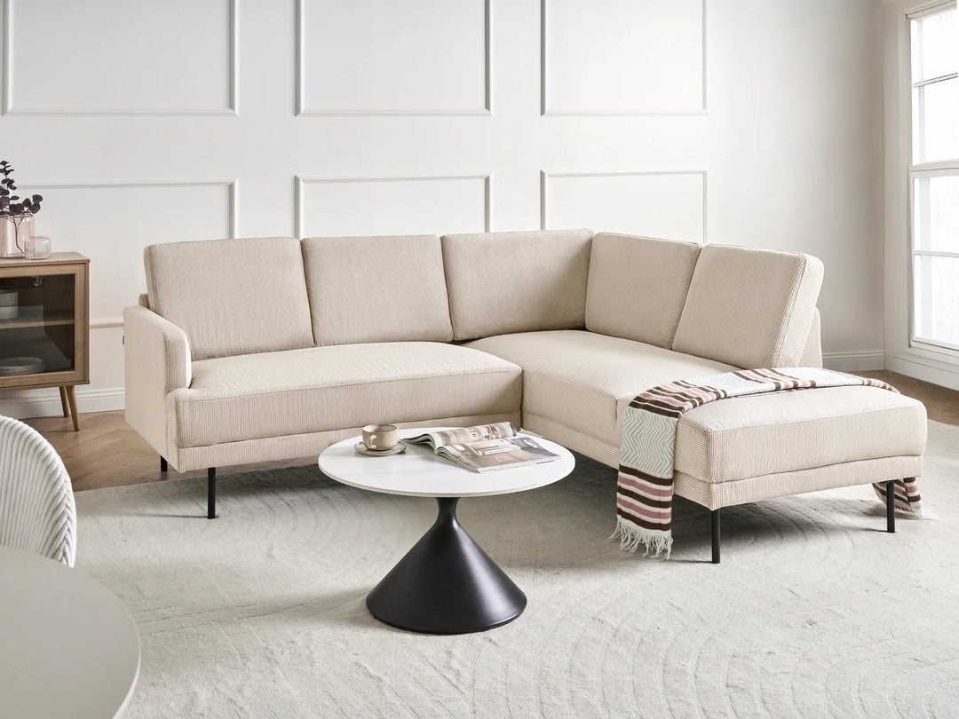 Beige sectional sofa in a modern living room with a white coffee table and decorative items.