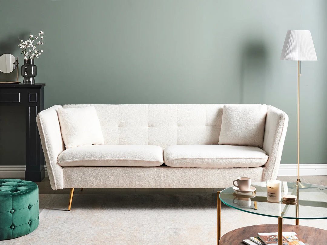 Beige sofa in a living room with a green wall, side table, and lamp.