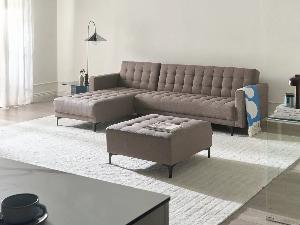 Gray sectional sofa with ottoman in a modern living room setting.