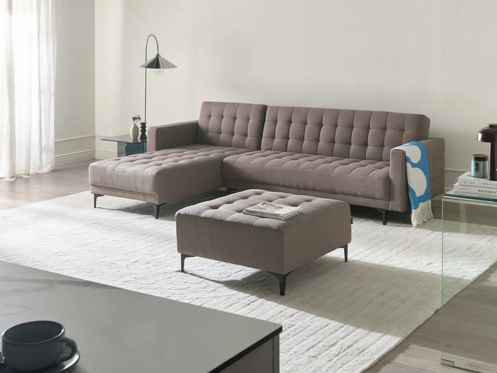 Gray sectional sofa with ottoman in a modern living room setting.