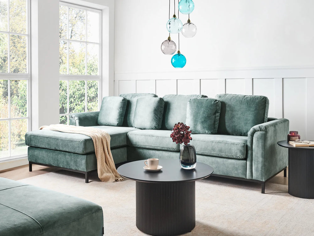 Modern living room with a green sectional sofa, coffee table, and decorative items.
