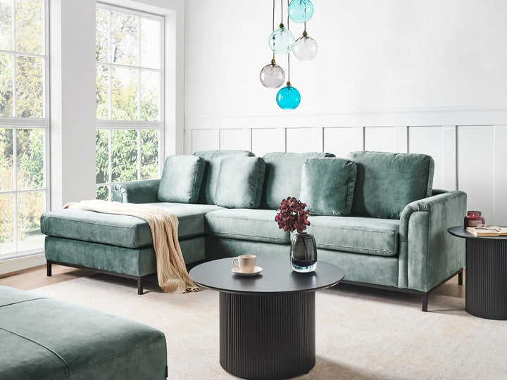 Modern living room with a green sectional sofa, coffee table, and decorative items.
