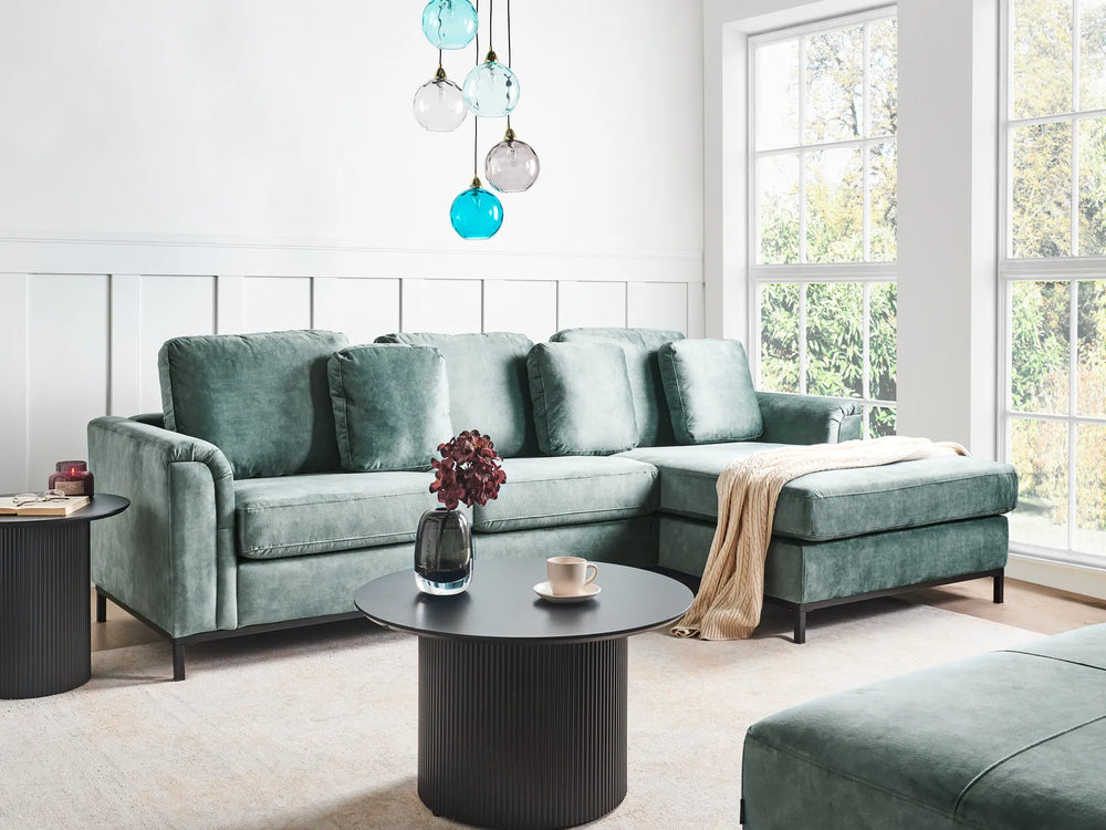 Modern living room with a green sectional sofa, coffee table, and decorative elements.
