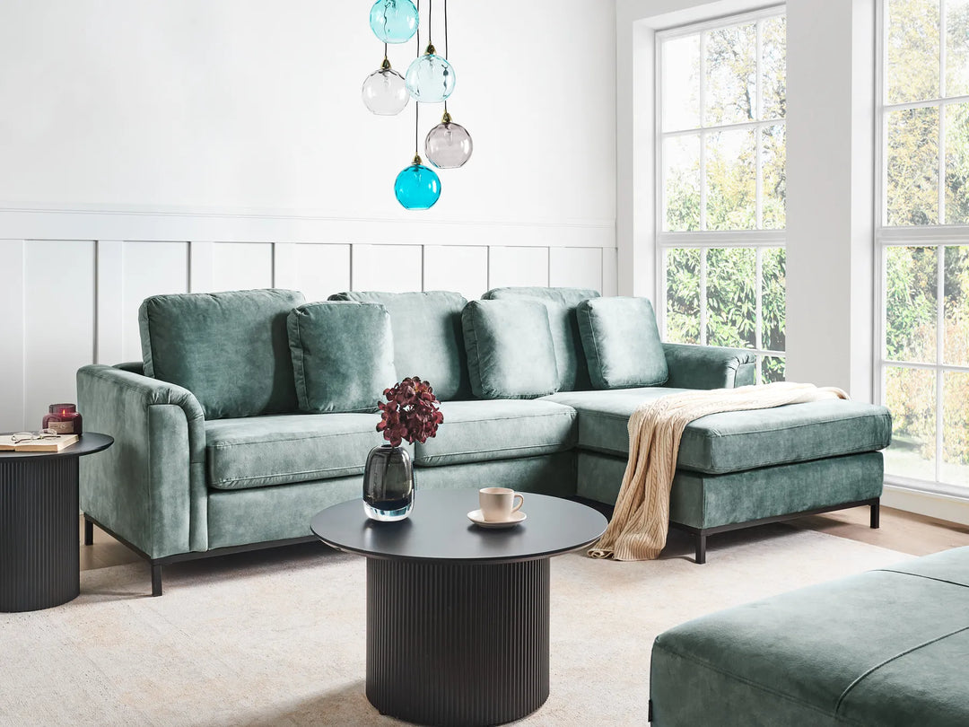 Modern living room with a green sectional sofa, coffee table, and decorative elements.
