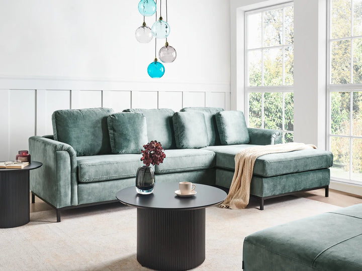 Modern living room with a green sectional sofa, coffee table, and decorative elements.