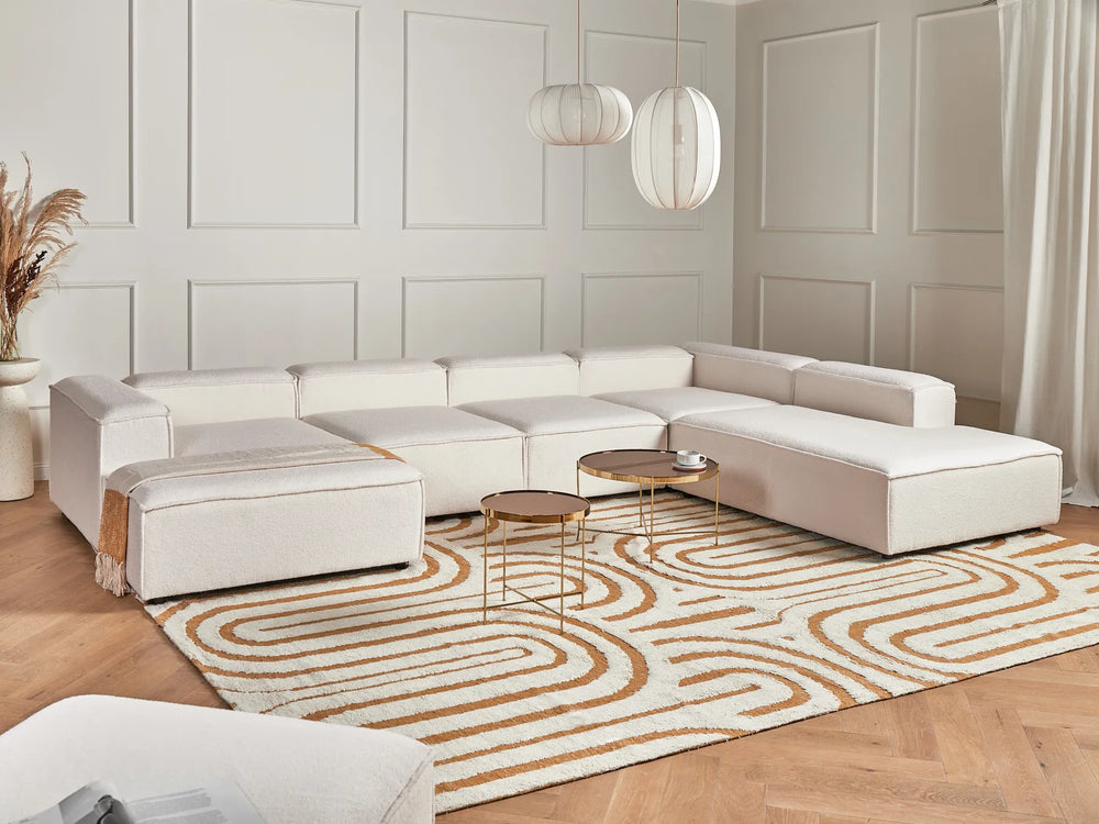 Modern living room with a white sectional sofa, coffee table, and decorative rug.