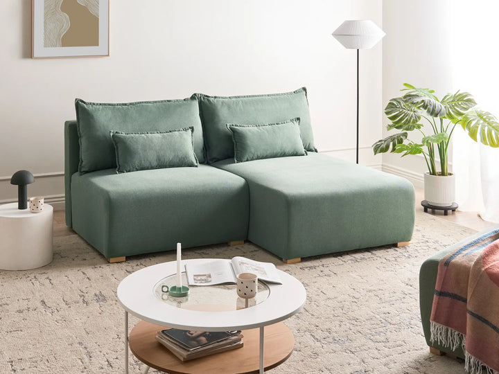 Modern living room with a green sectional sofa, round coffee table, and decorative elements.