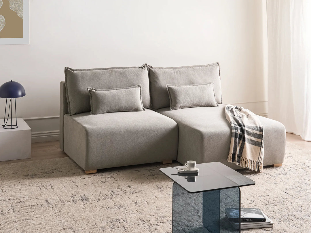 Gray sectional sofa in a living room with a coffee table and lamp.