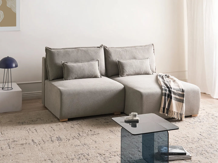 Gray sectional sofa in a living room with a coffee table and lamp.