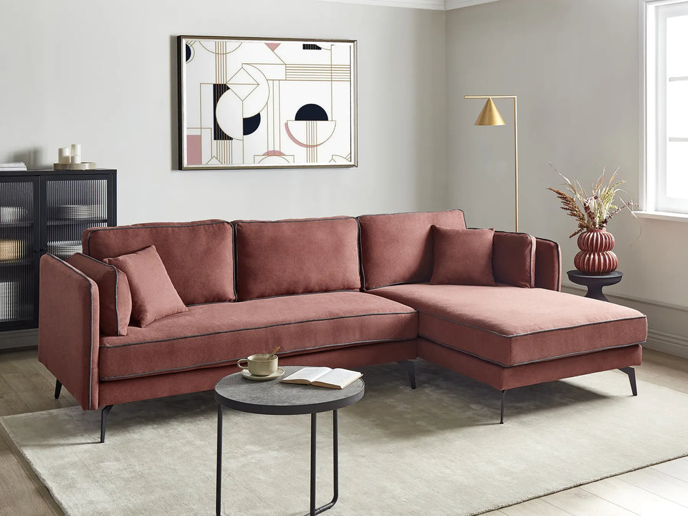 Modern living room with a pink sectional sofa, coffee table, and abstract art on the wall.