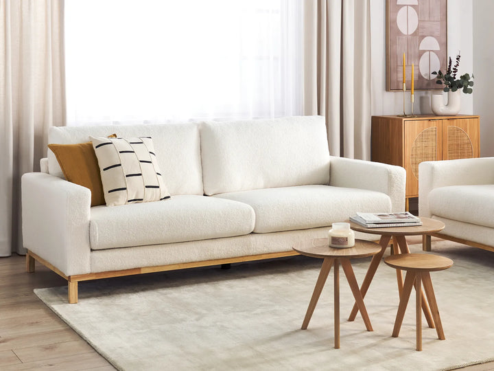 Modern living room with a white sofa, wooden coffee table, and side tables.