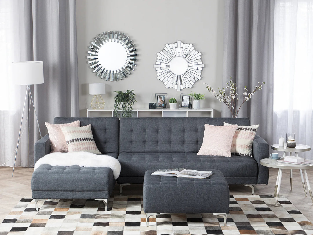 Modern living room with a gray sectional sofa, decorative mirrors, and a patterned rug.
