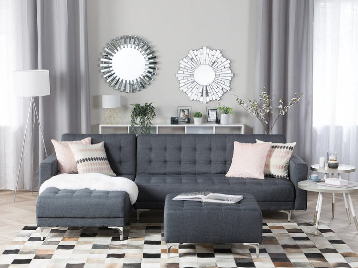 Modern living room with a gray sectional sofa, decorative mirrors, and a patterned rug.