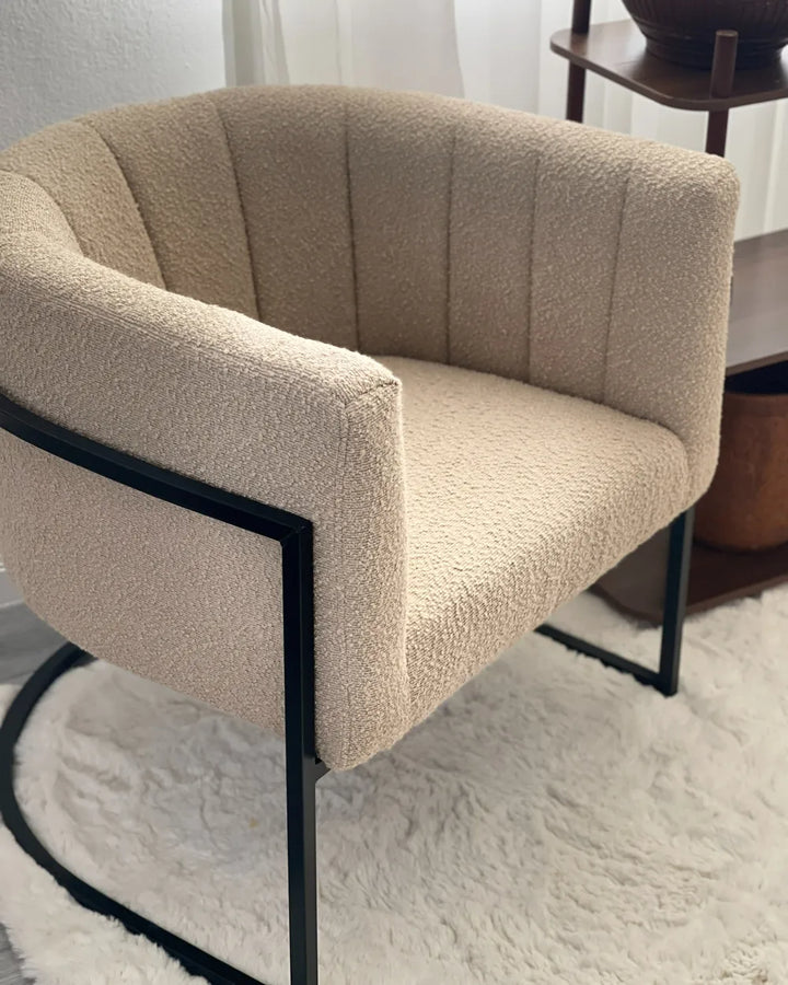Beige armchair with black metal frame on a white rug