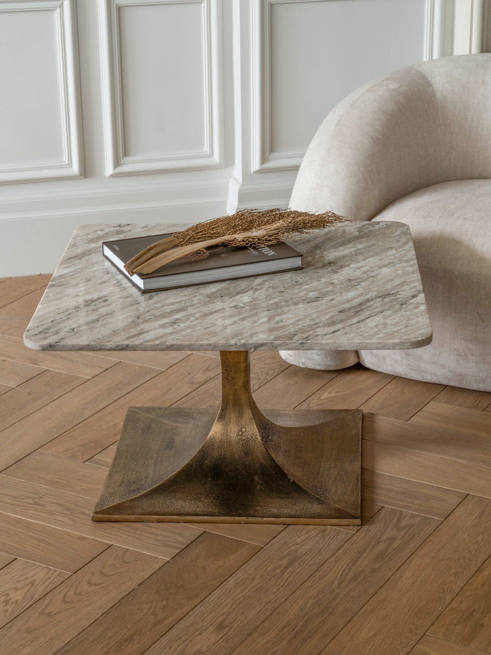 Marble-top side table with bronze base on a wooden floor