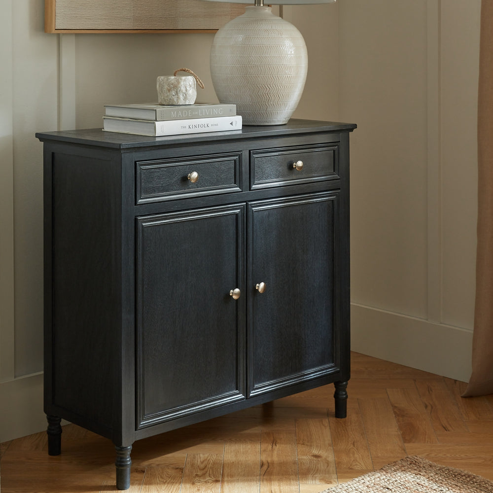 Dark wood cabinet with two doors and two drawers on a wooden floor.