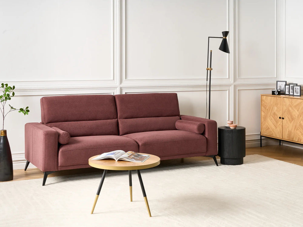 Maroon sofa in a modern living room with a coffee table and decorative items.