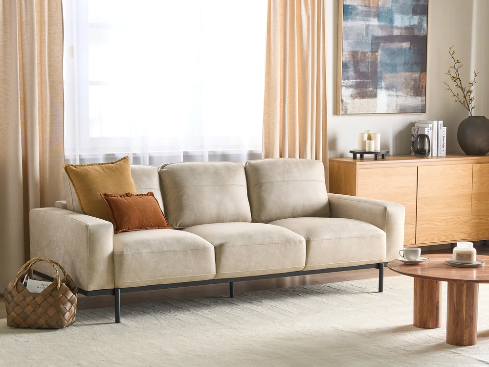 Beige sofa in a living room with a coffee table and decorative items.