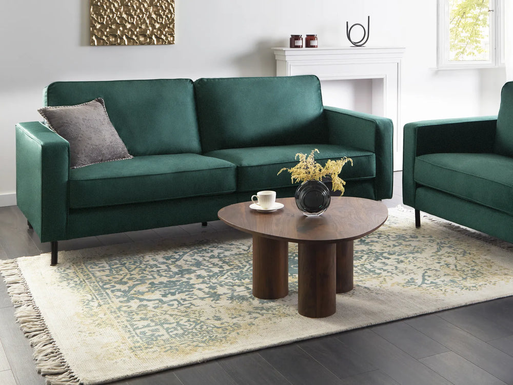 Green sofa in a living room with a wooden coffee table and decorative items.