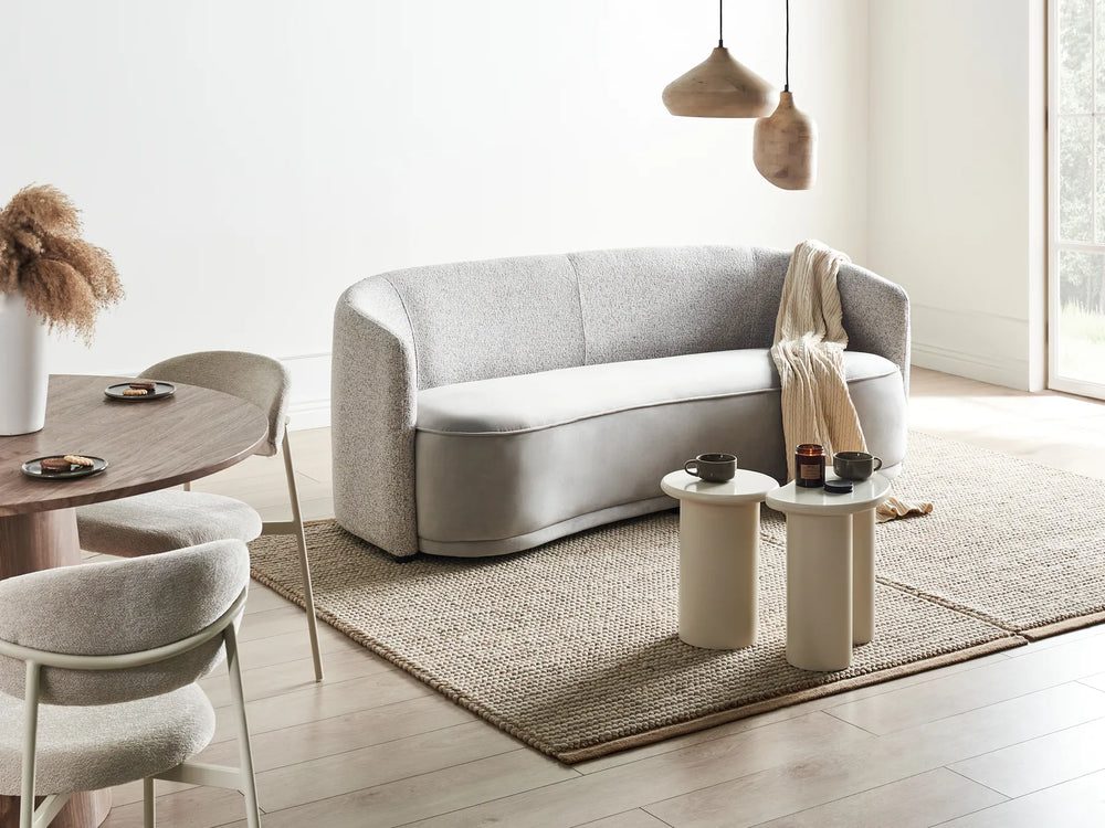 Modern living room with a gray sofa, dining table, and chairs.