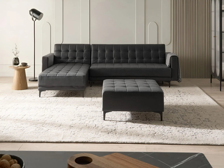 Gray sectional sofa with ottoman in a modern living room setting.