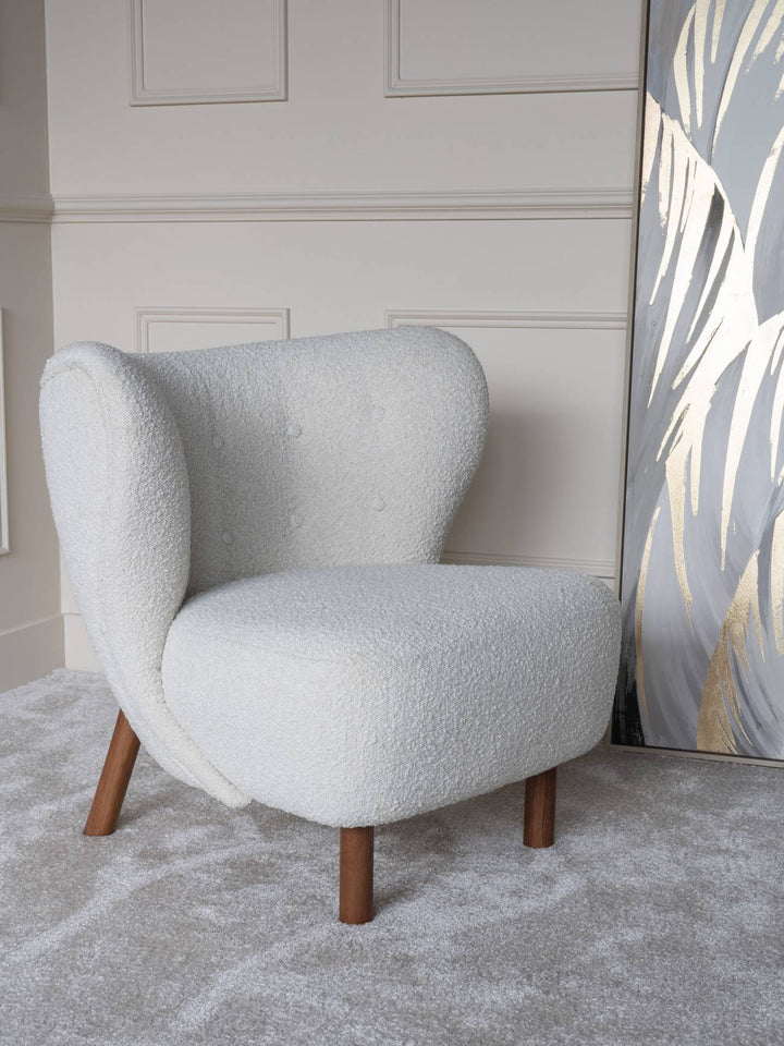 White textured armchair with wooden legs in a room with a decorative wall panel.