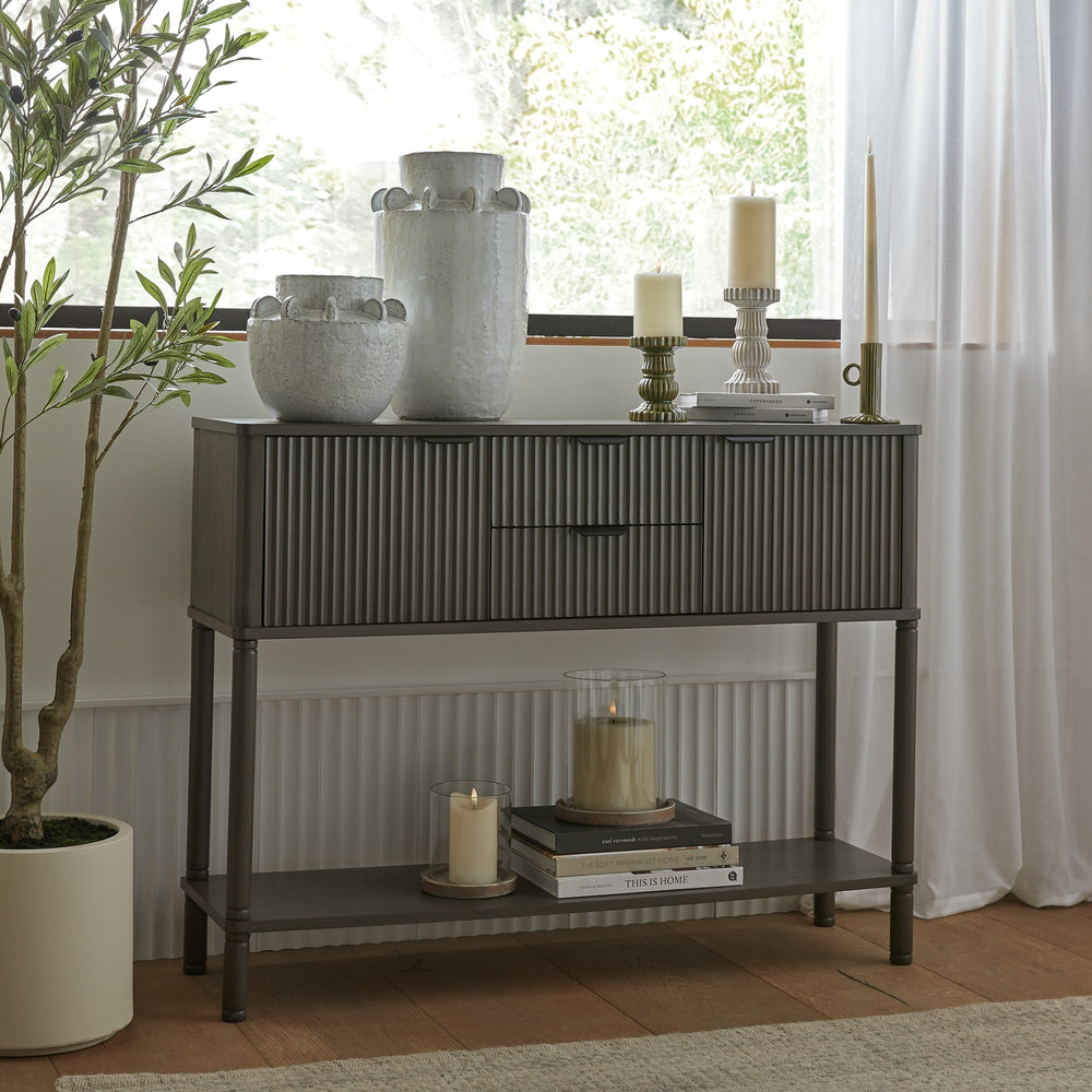 Console table with decorative items in a room with a window and plant