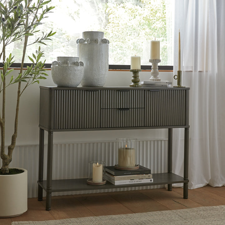 Console table with decorative items in a room with a window and plant