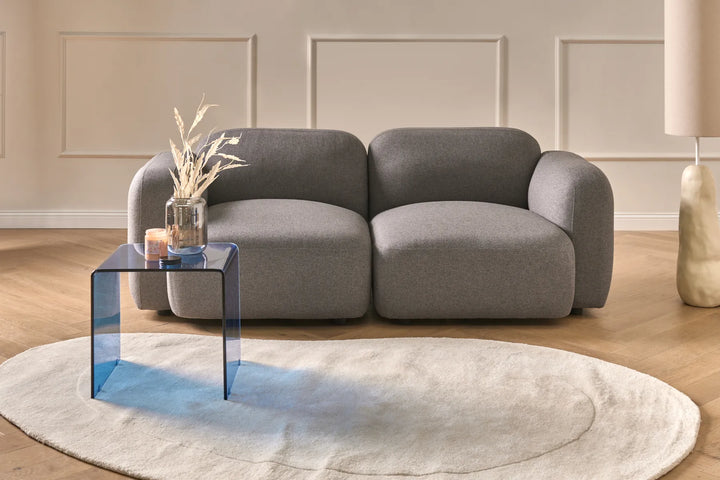 Gray sofa in a living room with a clear glass coffee table and decorative elements.