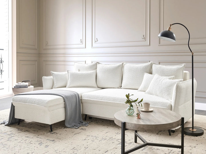 Modern living room with a white sectional sofa, round wooden coffee table, and floor lamp.