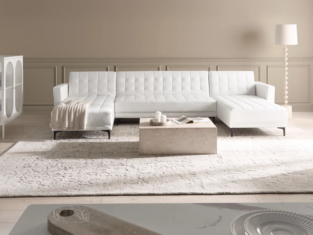 Modern living room with a white sectional sofa, coffee table, and rug.